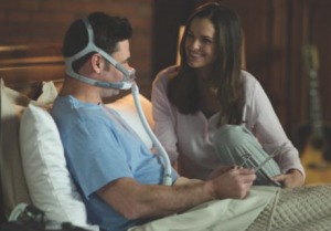 Man wearing his CPAP face mask and talking to wife before bed