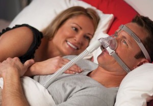 Woman smiling at her husband while he is wearing his CPAP nose mask