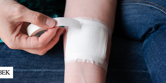 Person wrapping their wound with a gauze and taping it with white tape