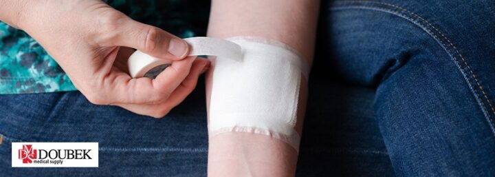 Person wrapping their wound with a gauze and taping it with white tape