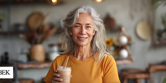 Doubek-HealthyAgingMonth Older woman smiling and holding a smoothie in her hand
