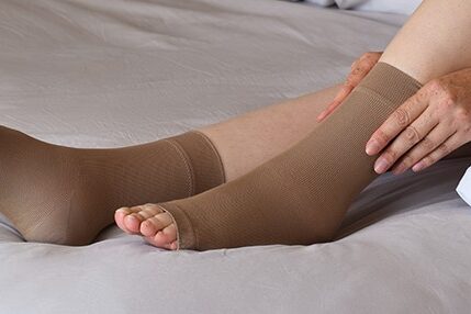 Woman pulling compression sock onto foot