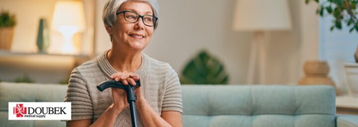 Older woman sitting on couch smiling with her hands on a cane