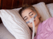 Woman lying down on bed with CPAP mask on her face