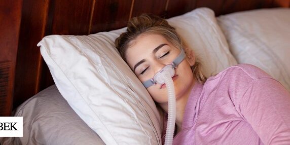 Woman lying down on bed with CPAP mask on her face