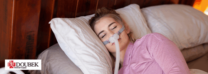 Doubek-CPAPImproveLife Woman lying down on bed with CPAP mask on her face