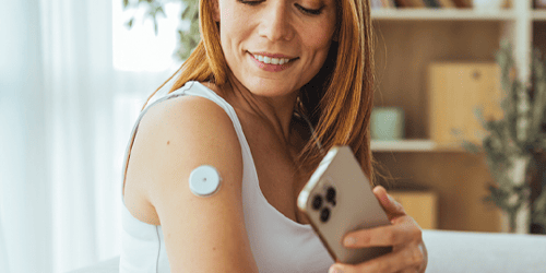 A woman using her phone to check her CGM