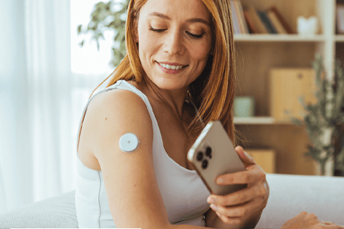 A woman using her phone to check her CGM