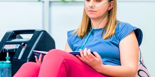 Woman on home oxygen therapy sitting in a chair reading a book