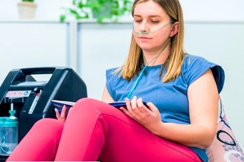 Woman on home oxygen therapy sitting in a chair reading a book