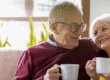 Happy elderly couple enjoying a beverage on the couch