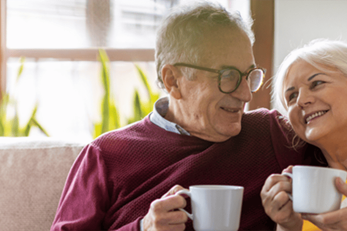 Happy elderly couple enjoying a beverage on the couch