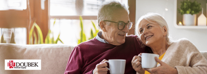 Happy elderly couple enjoying a beverage on the couch