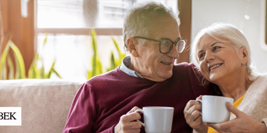 Happy elderly couple enjoying a beverage on the couch